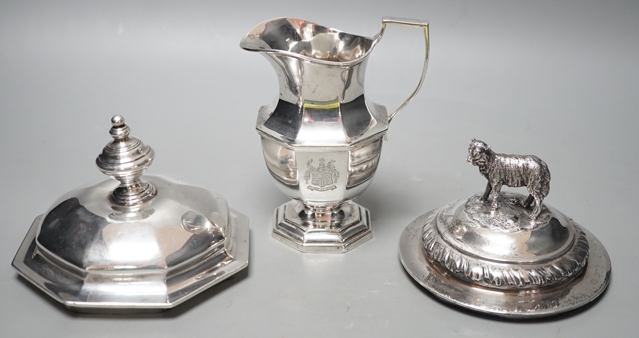A 20th century silver cream jug by Mappin & Webb(date letter rubbed), height 13.9cm and two Victorian trophy cup covers, one with sheep finial, 24.8oz.